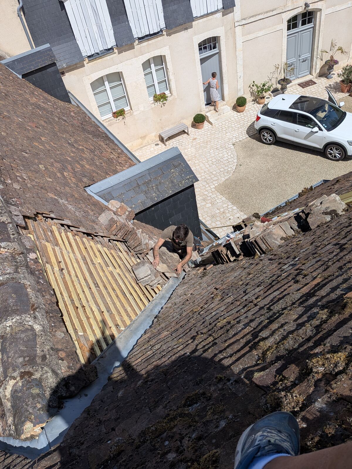 Couvreur posant des tuiles sur un toit ancien en Touraine